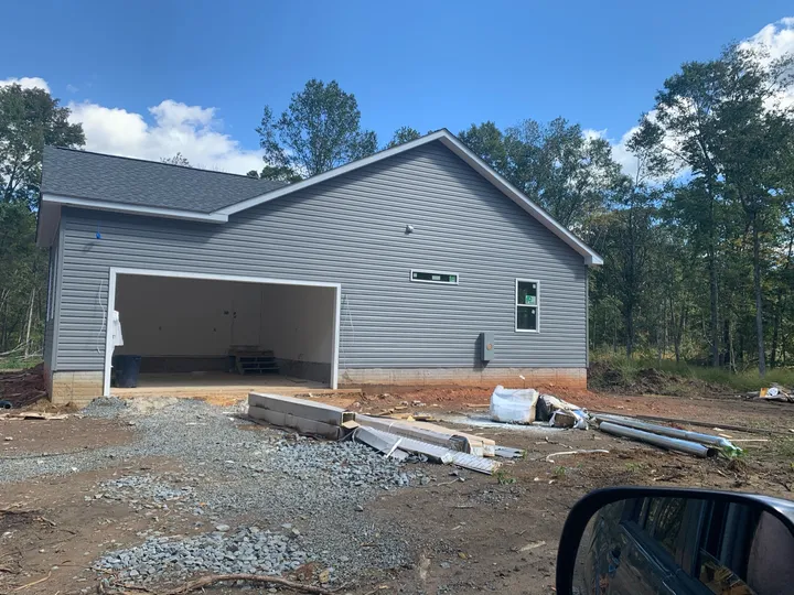 Side-entry garage elevation with siding and windows during house construction