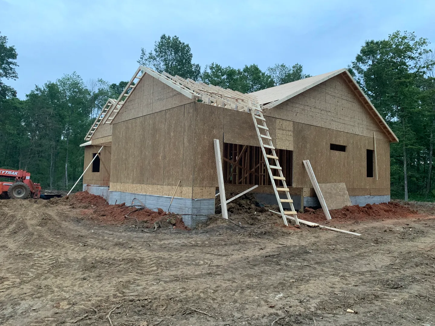 Wood-framed house with wall sheathing and roof framing in progress
