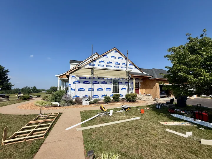 New sheathing exposed beside the garage with housewrap covering the adjacent wall