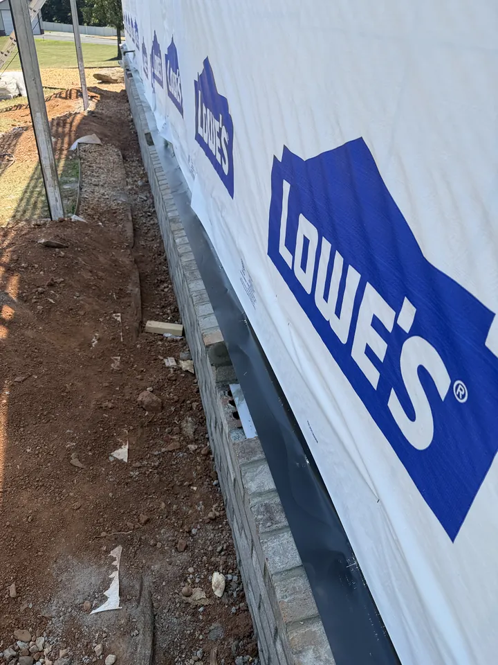 Housewrap and metal flashing at the base of the wall after stone veneer removal